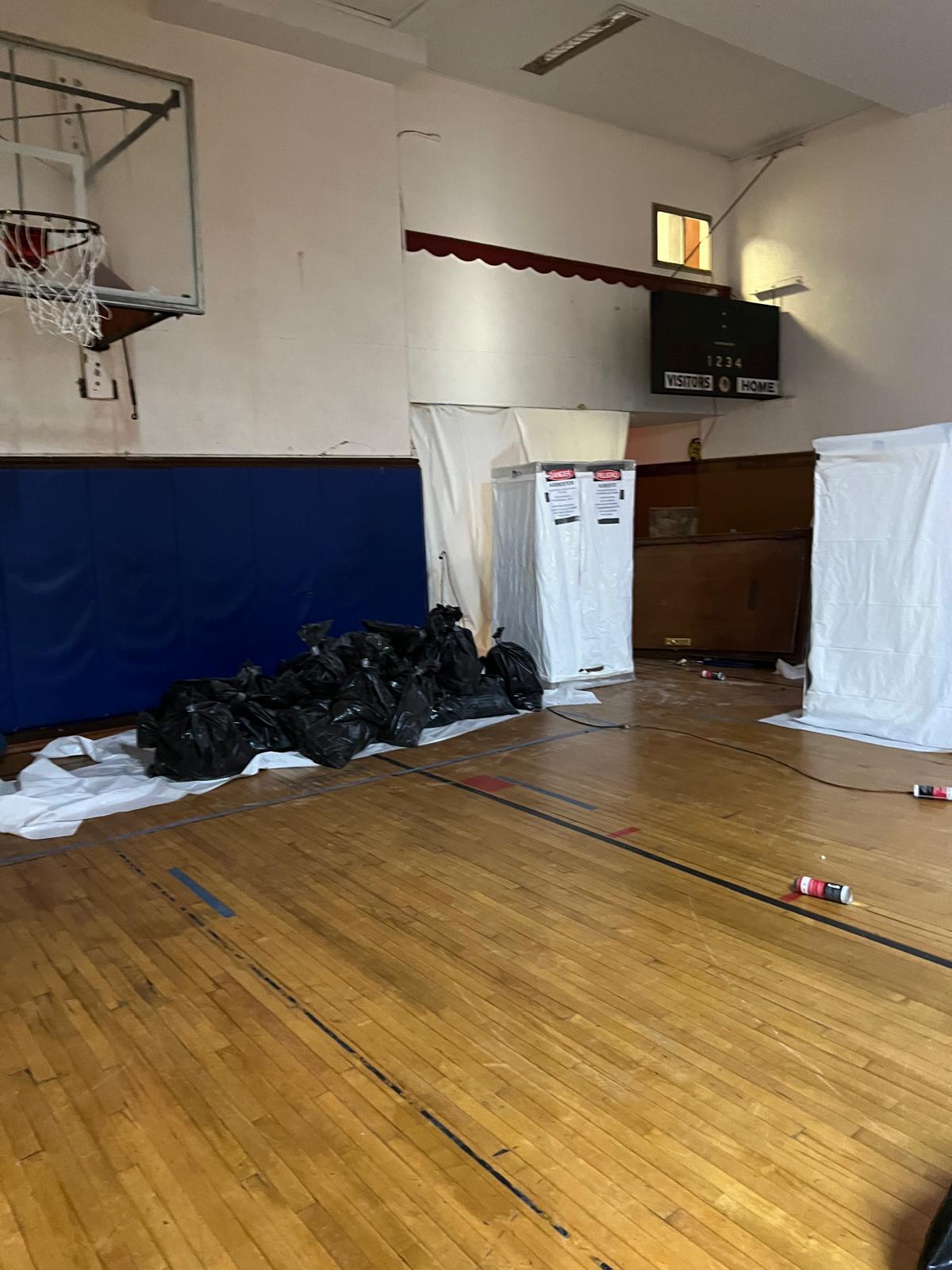 Sealed asbestos containment and bagged waste inside a school gymnasium