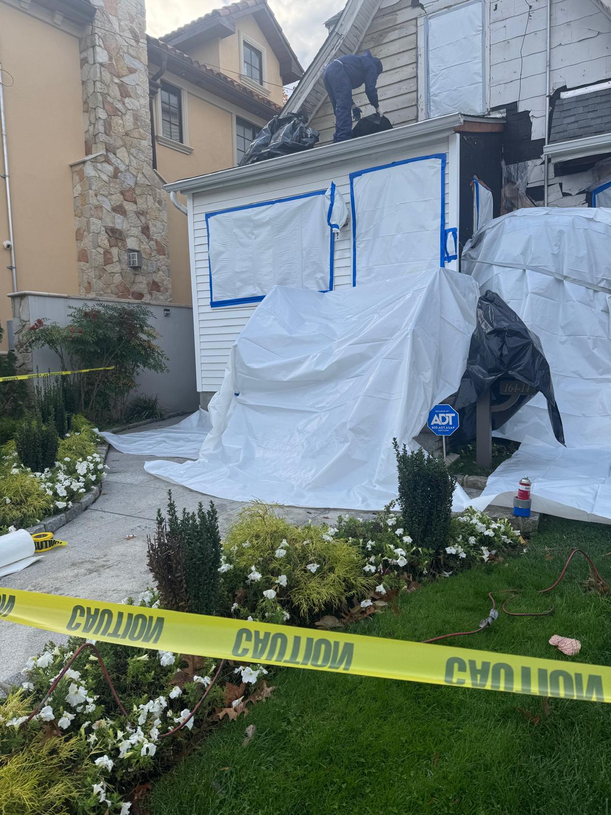 Poly sheeting, taped window protection and caution tape around a residential abatement site